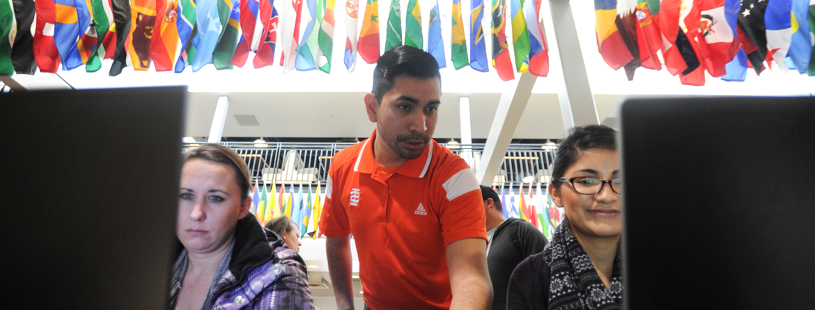 Students receiving registration help from ISU employee with international flags in the background